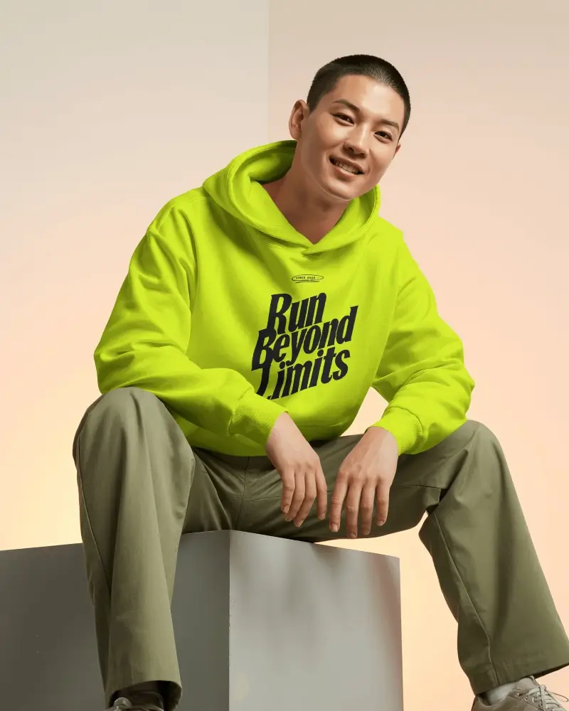 Warm Gradient Studio Hoodie Mockup Male Model Seated On Cube In Relaxed Pose