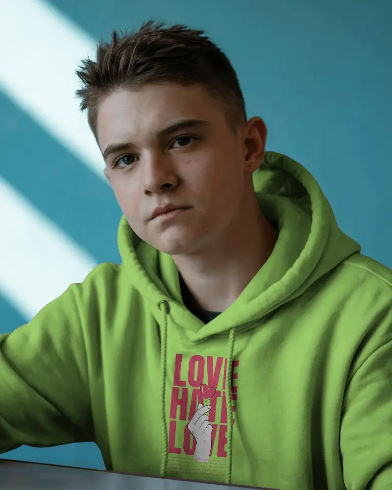 Casual Interior Hoodie Mockup Young Male Model Facing Camera With Natural Window Light And Teal Wall 0591