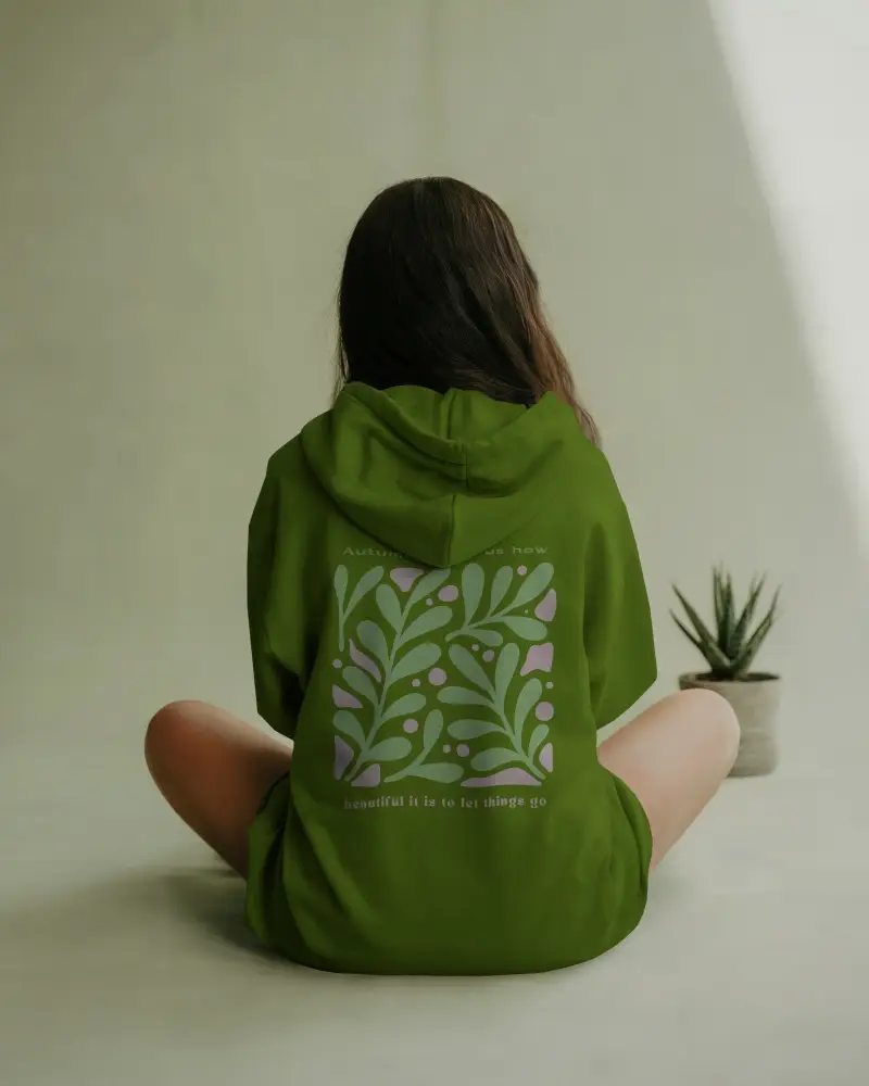Minimalist Nature Hoodie Mockup Female Model Sitting On Floor With Plant Soft Sunlight Calm Neutral Background