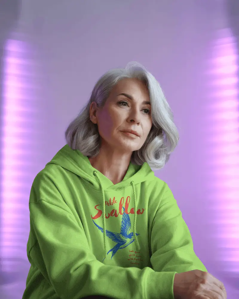 Hoodie Mockup Older Woman Model In Soft Purple Lighting With Contemplative Expression