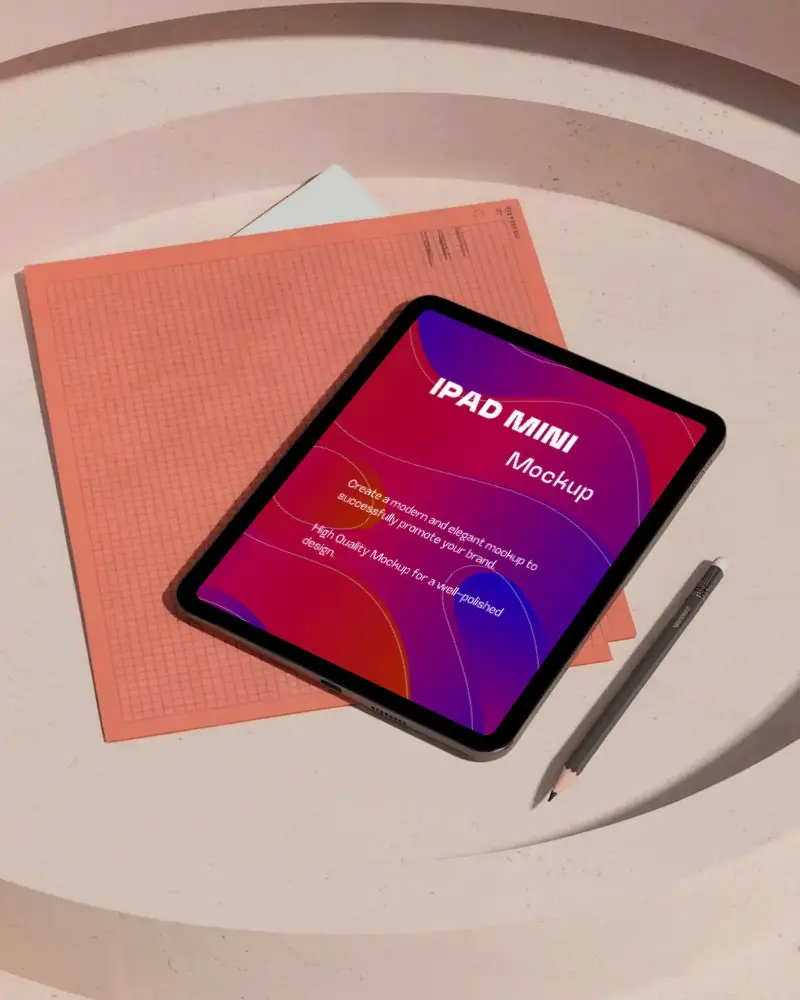 Ipad Mini Mockup Flatlay On Round Beige Tabletop With Orange Graph Sheet And Pencil Stationery