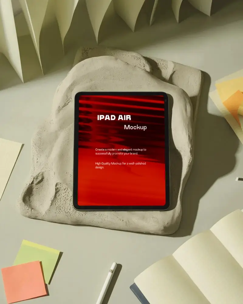 Artistic Ipad Air Mockup Embedded In Stone Texture With Open Notebooks And Stationery Around