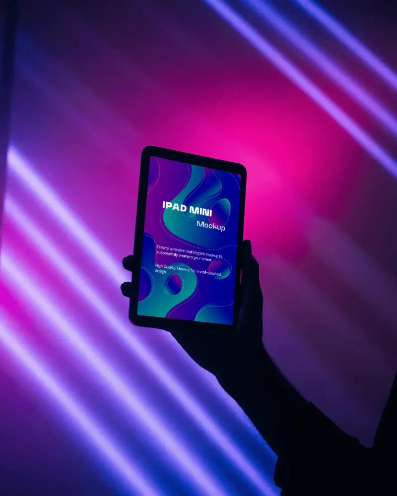 Editable Ipad Mini Mockup Hand Holding Device Against Modern Neon Lighting Studio Glow