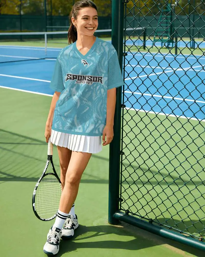 V Neck Tennis Jersey Mockup Female Model Standing Beside Court Fence With Racket And Sporty Skirt