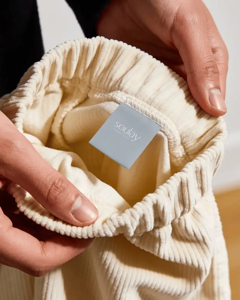 Hand Holding Clothing Label Mockup Inside Elastic Waistband Corduroy Pants Close Up