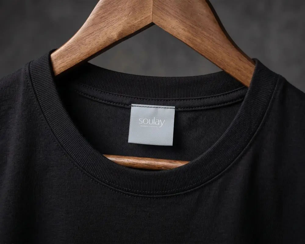 Blank Clothing Label Mockup On Crewneck Tshirt Hanging On Wooden Hanger Closeup View