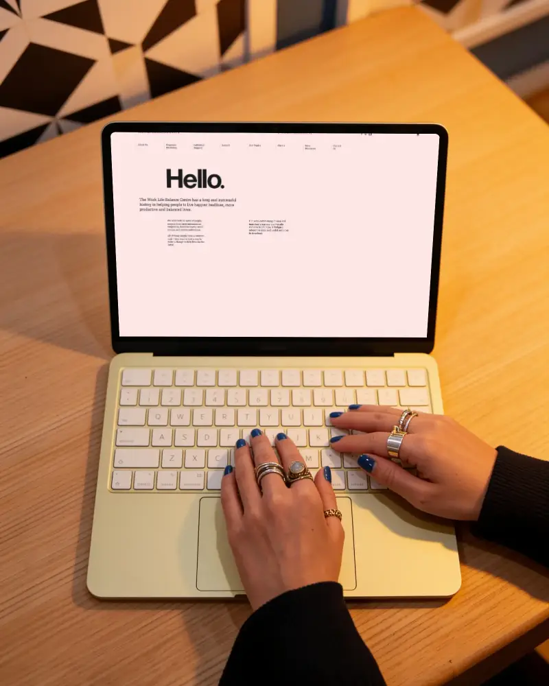Person Using Macbook Neo Laptop With Accessories Rings On Fingers On Workspace Tabletop