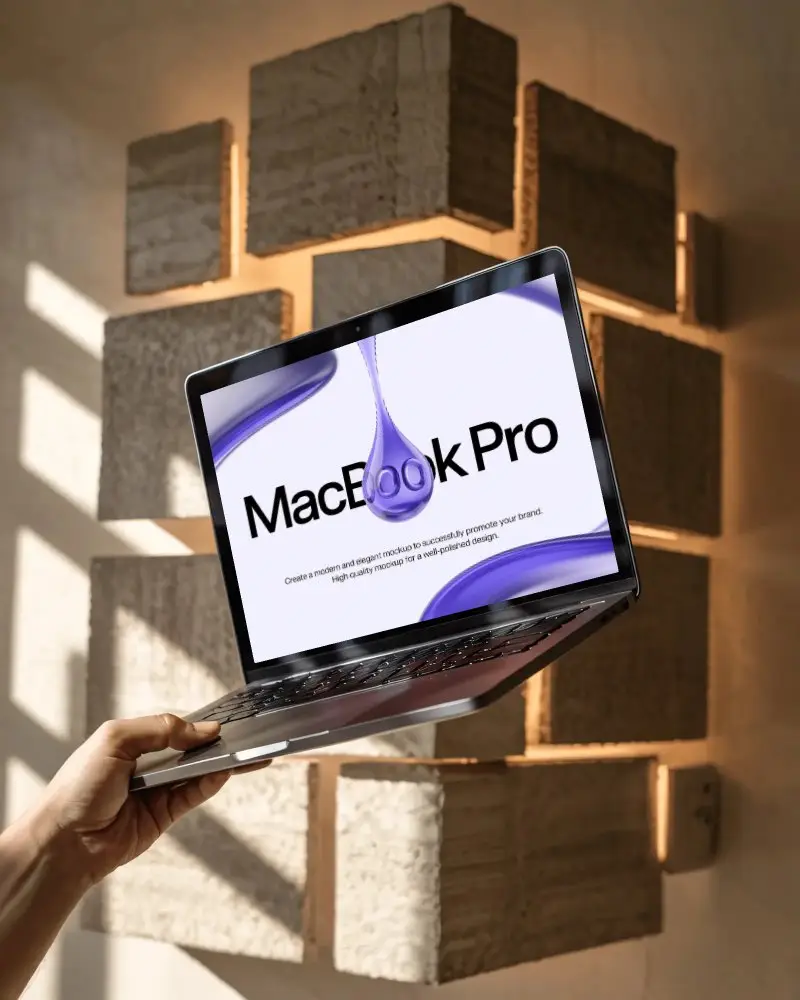 hand-held-macbook-m1-pro-mockup-in-sunlit-room-with-textured-block-wall-and-soft-shadows