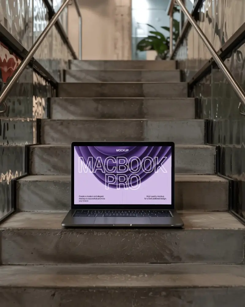 M1 Pro Mockup On Modern Metal Staircase In Industrial Interior With Warm Natural Light
