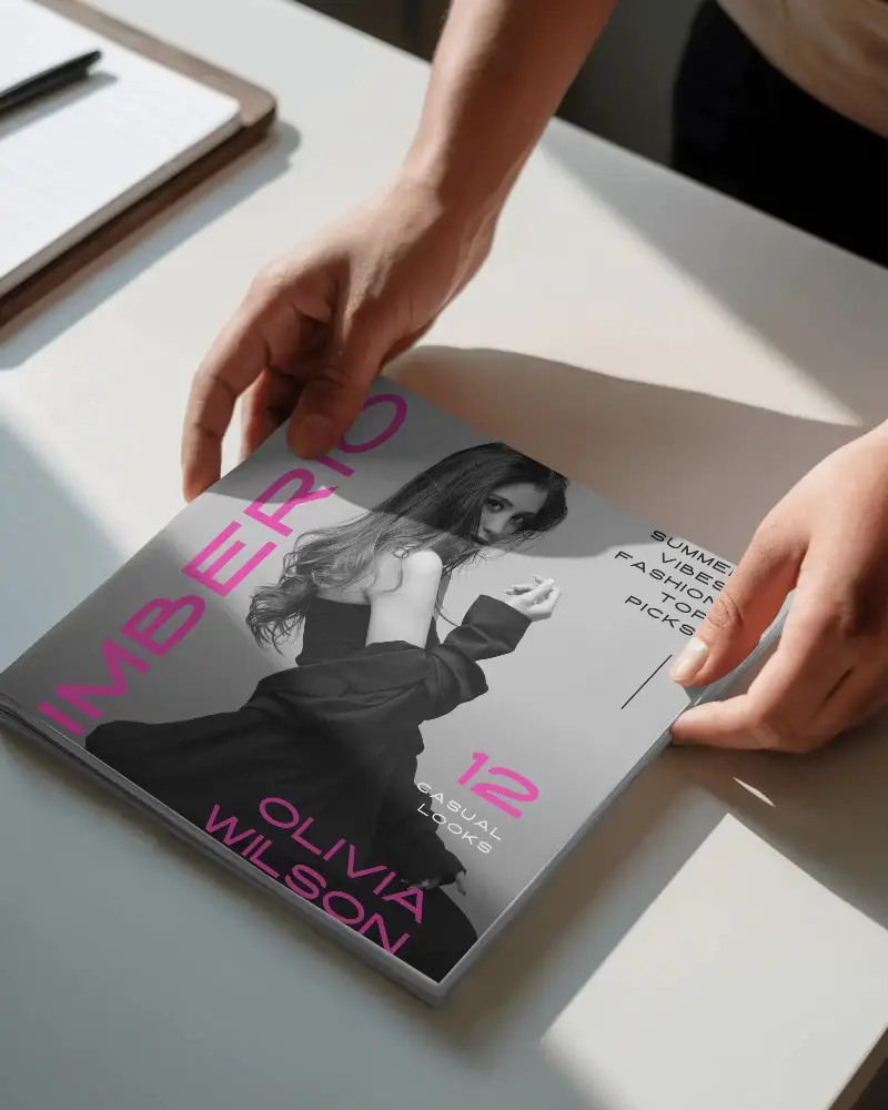 Hands Holding Square Magazine On Minimalist Desk With Natural Light Shadow Effects