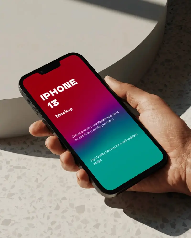 Iphone 13 Mockup Hand Holding Device On Speckled Surface With Soft Sunlight And Minimal Shadow Play