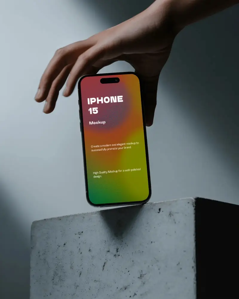 iphone-15-mockup-hand-holding-smartphone-over-minimalist-concrete-block-in-moody-light