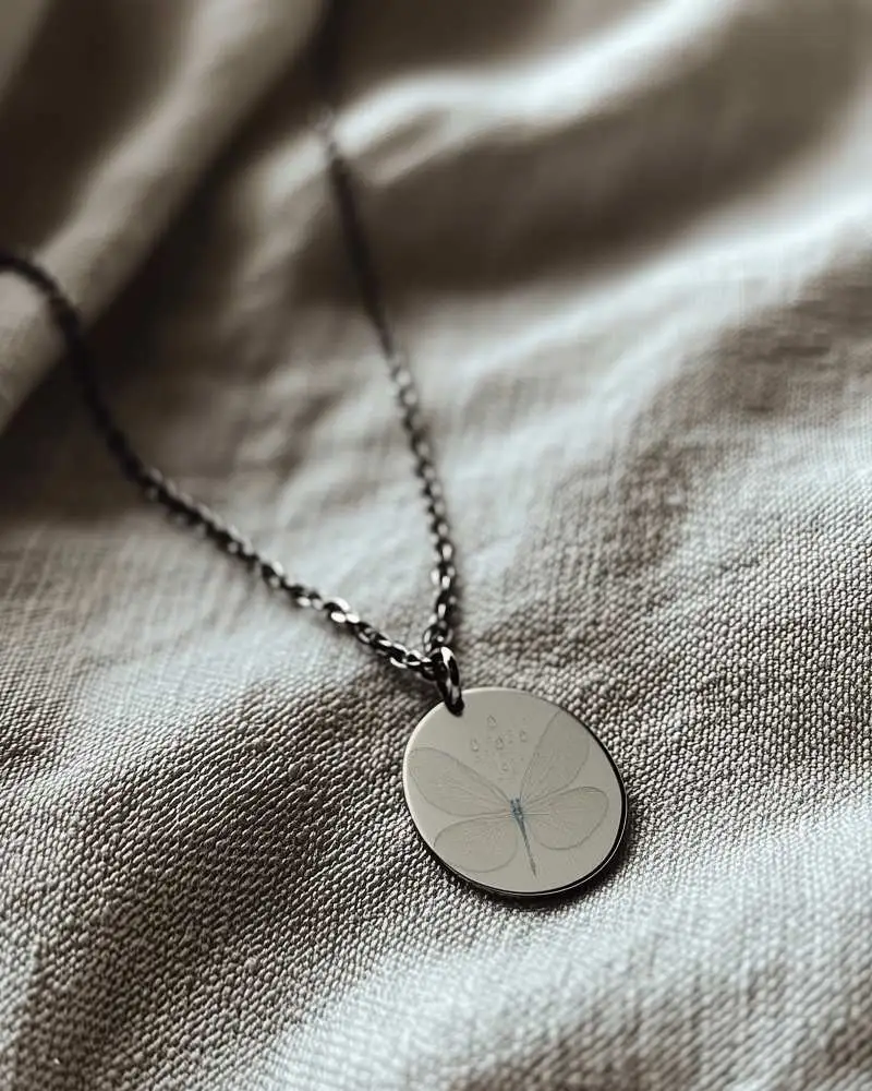 Matte Black Round Pendant Necklace Mockup On Cream Textile Surface Artistic Lighting Jewelry Scene