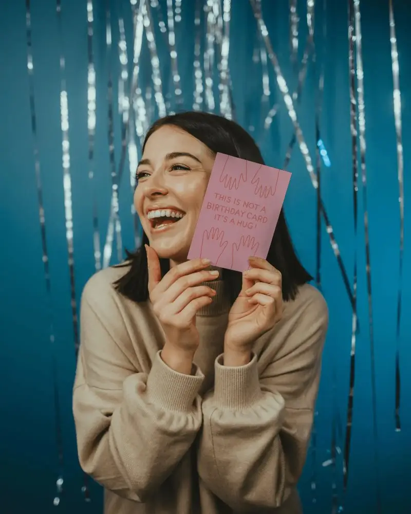 Joyful Woman Holding New Year Invitation Card Mockup With Shiny Party Background Celebration