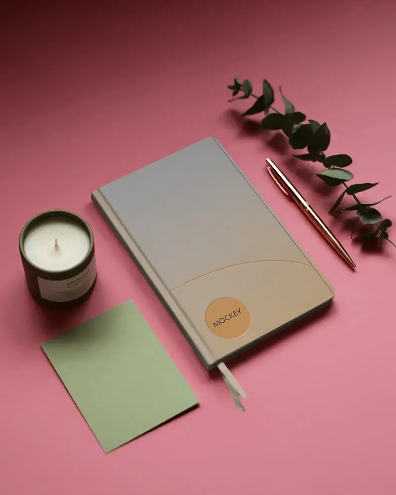 Minimalist Notebook Mockup With Candle Pen And Eucalyptus On Soft Pink Background