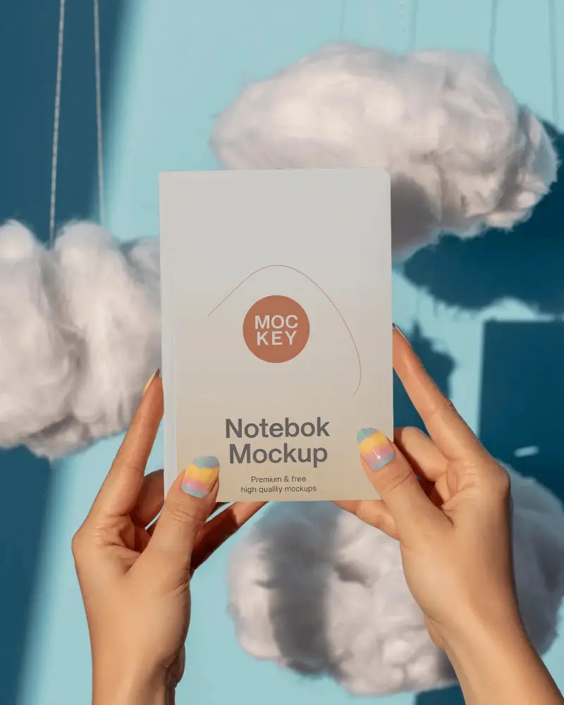 Floating Clouds Notebook Mockup Held Up Against Bright Blue Sky Inspired Backdrop