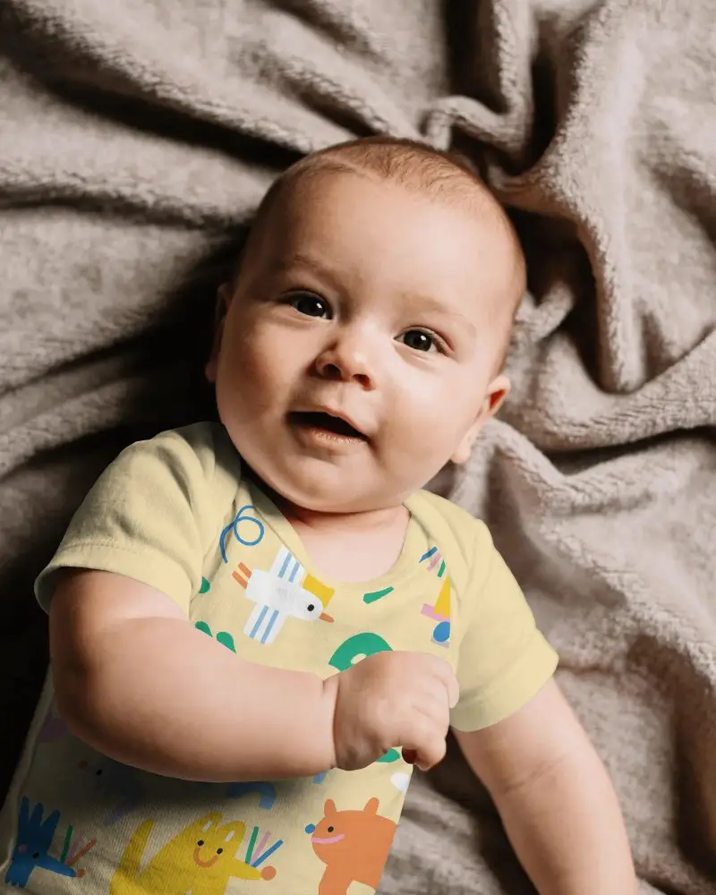 Soft Breathable Baby Onesie Mockup On Infant Lying On Cozy Textured Blanket Background