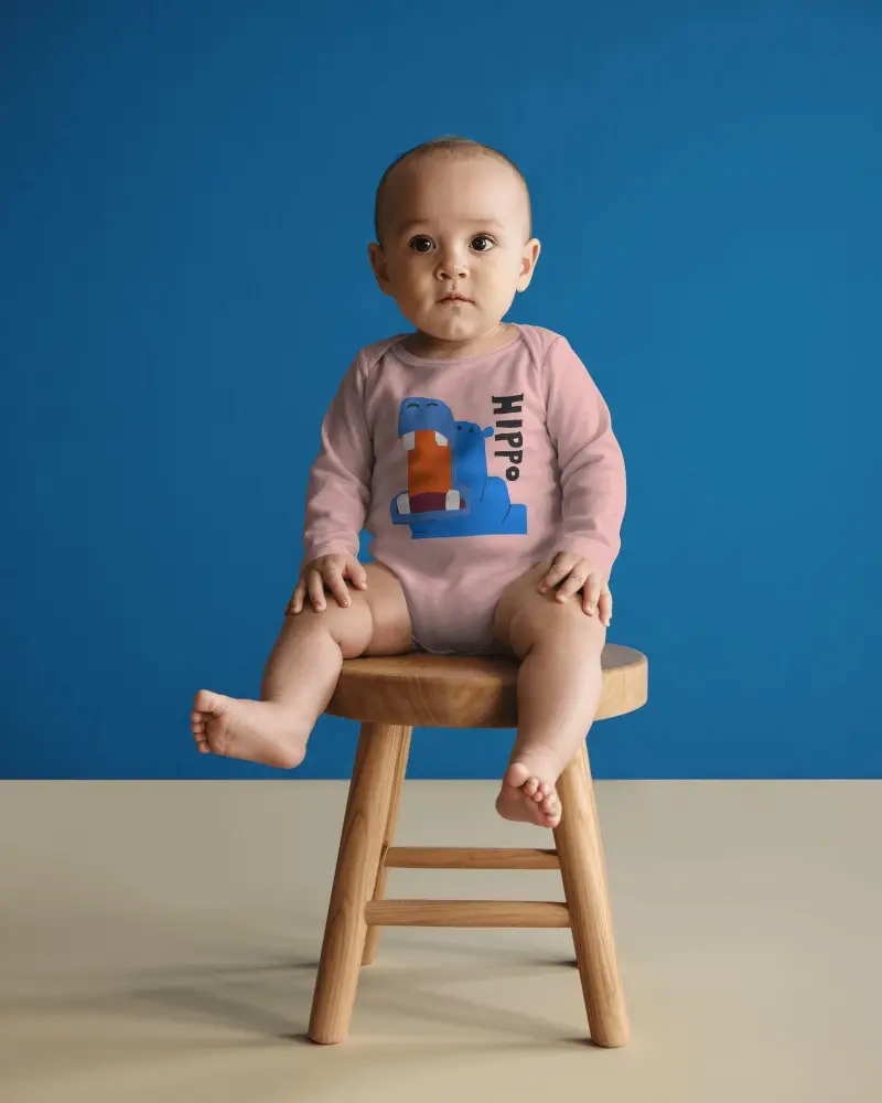 Studio Baby Onesie Mockup Infant Sitting On Wooden Stool Solid Blue Background