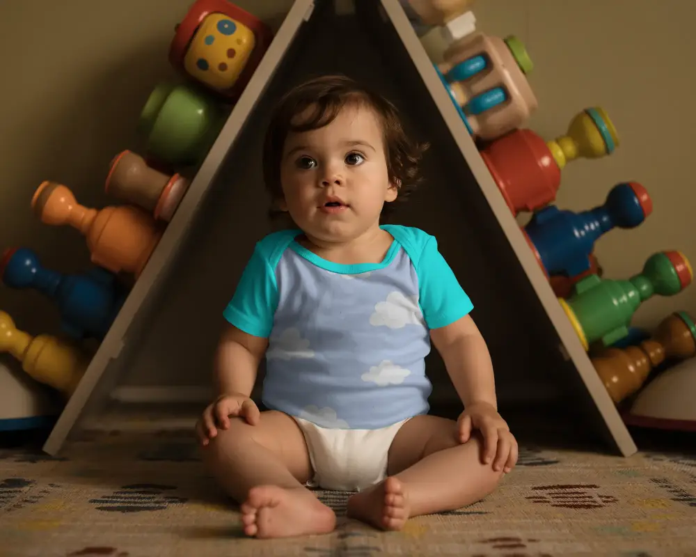 Infant Short Sleeve Onesie Mockup Baby Wearing Casual Outfit Sitting At Playroom With Decor