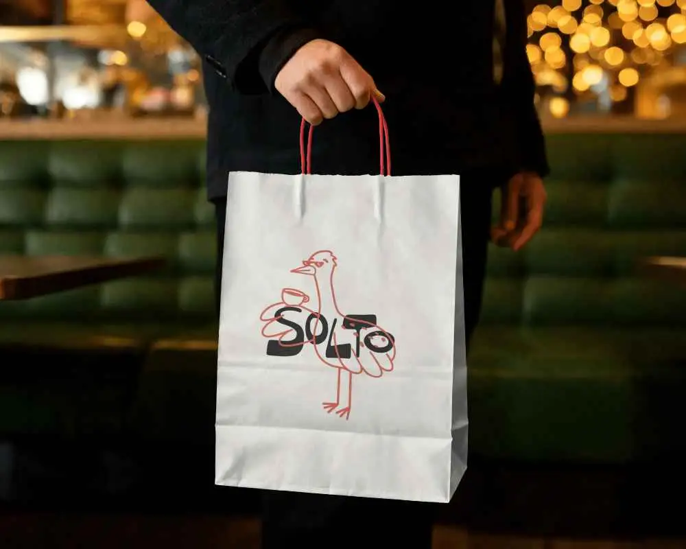 Person Holding Minimalist Paper Bag Mockup For Branding And Packaging Designs