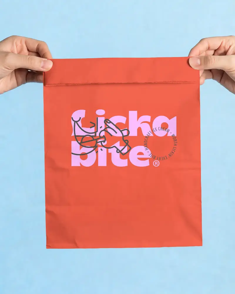 Eco Friendly Paper Bag Mockup With Closed Top Held By Hands On Blue Background