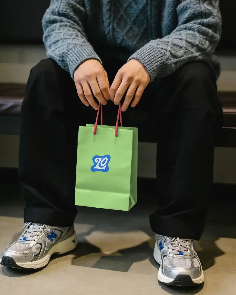 Casual Seated Person Displaying Portable Paper Bag Mockup Promotional Branding Use
