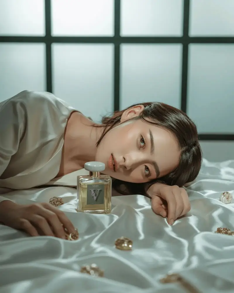 Elegant Perfume Mockup Female Model Lying On Satin Bed With Golden Bottle