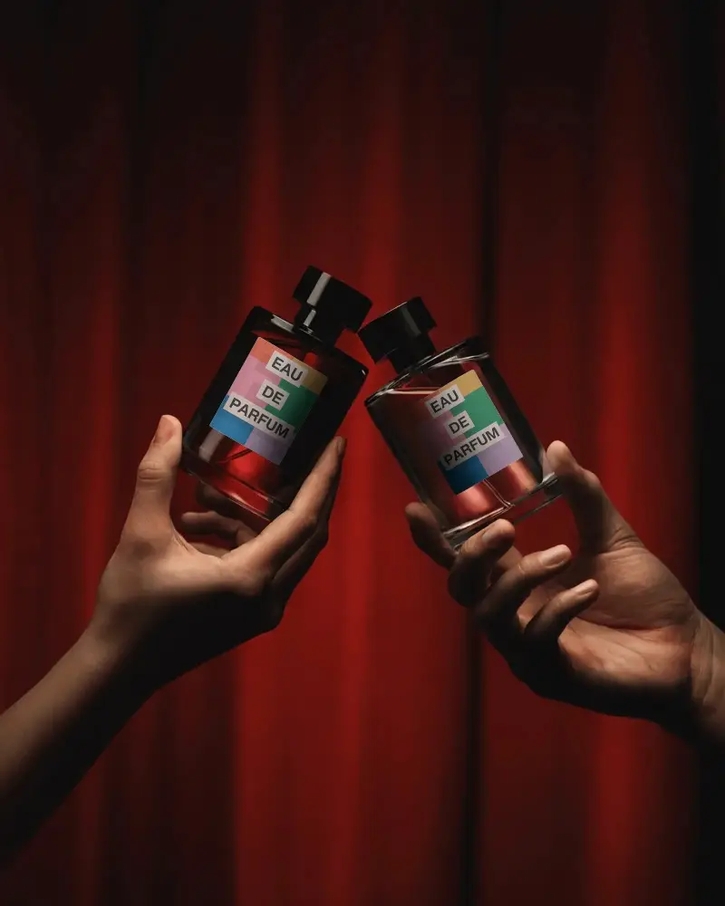 Luxury Perfume Mockup Dual Glass Bottles Held In Hands Dramatic Red Curtain Background