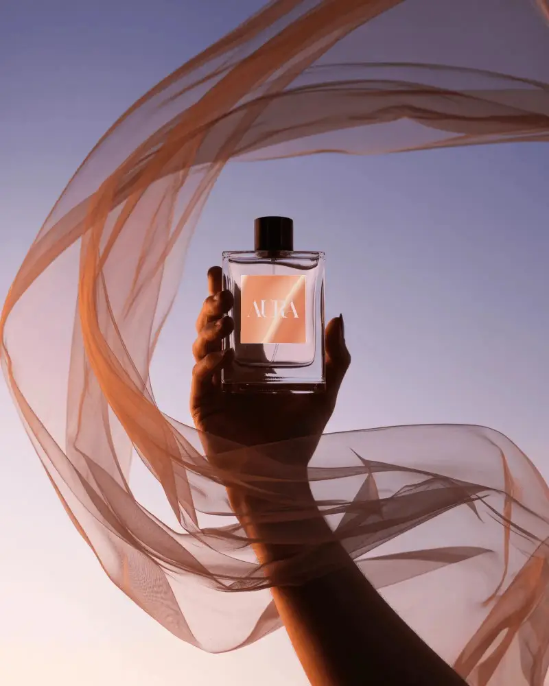 luxury-perfume-bottle-mockup-handheld-against-sunset-sky-with-flowing-sheer-fabric-elegant-scene