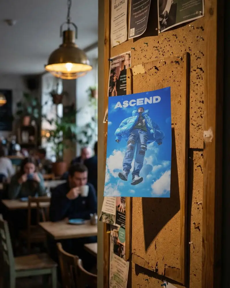 Vertical Paper Poster Mockup On Textured Cork Board Inside Busy Coffee Shop Setting