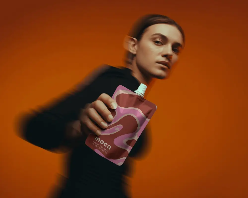 Dynamic Spout Pouch Mockup Held By Model With Motion Blur On Bold Orange Background