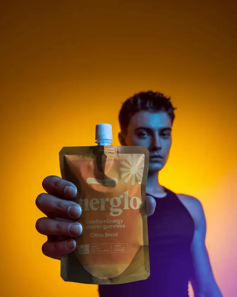 Spout Pouch Mockup Held Forward By Model With Bold Yellow Orange Studio Light