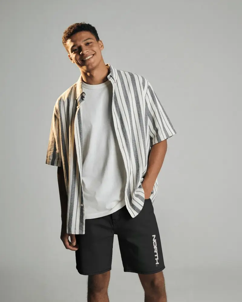 Tilted Pose Shorts Mockup Male Model Leaning Sideways Relaxed Smile Clean Studio Background