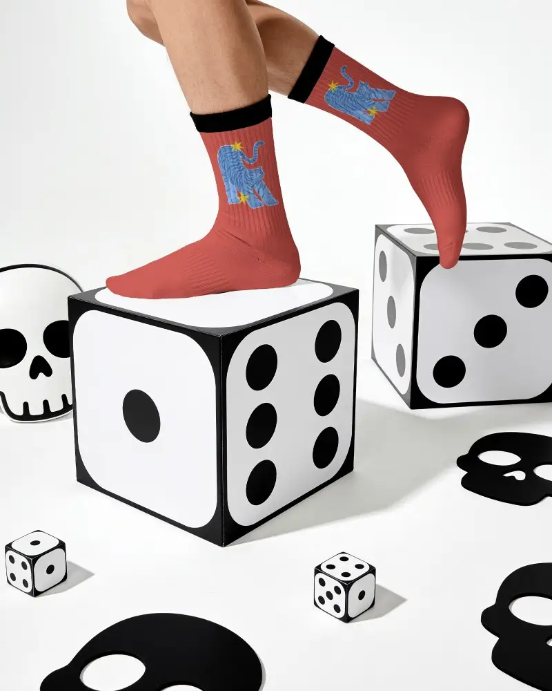 Playful Socks Mockup With Model Balancing On Oversized Dice In Graphic Skull Themed Studio