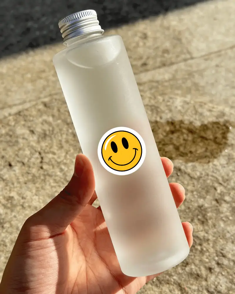 Realistic Cosmetic Bottle Sticker Mockup With Frosted Glass Effect And Metallic Lid Held In Hand