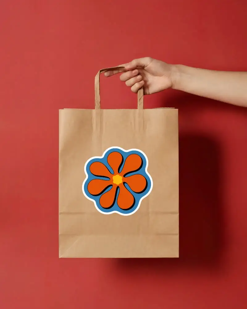 Minimal Kraft Paper Bag Sticker Mockup With Hand Holding On Bold Red Background For Brand Showcase