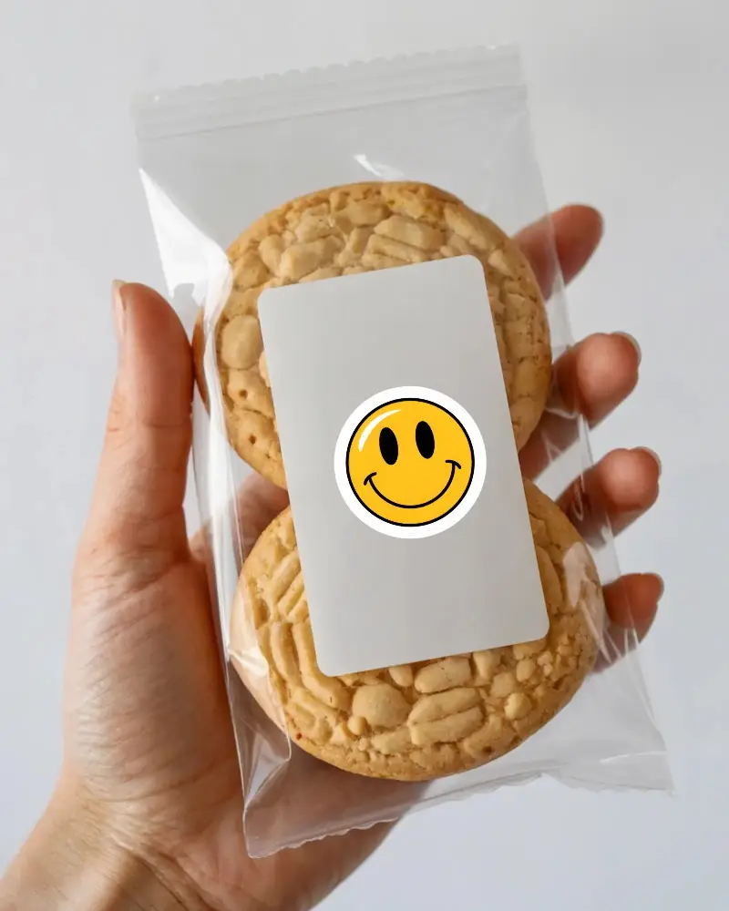 Hand Holding Transparent Cookie Packaging With Blank Rectangular Sticker Mockup