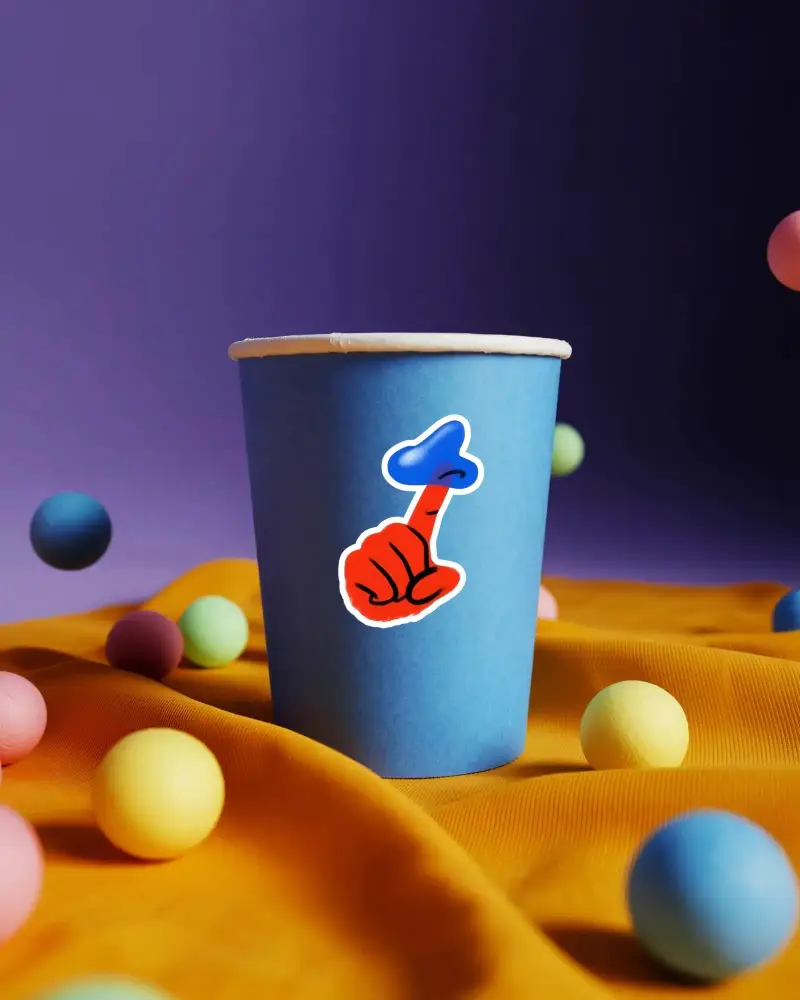 Isolated Blue Cup Sticker Mockup With Floating Ball Decor On Bright Fabric Textured Surface