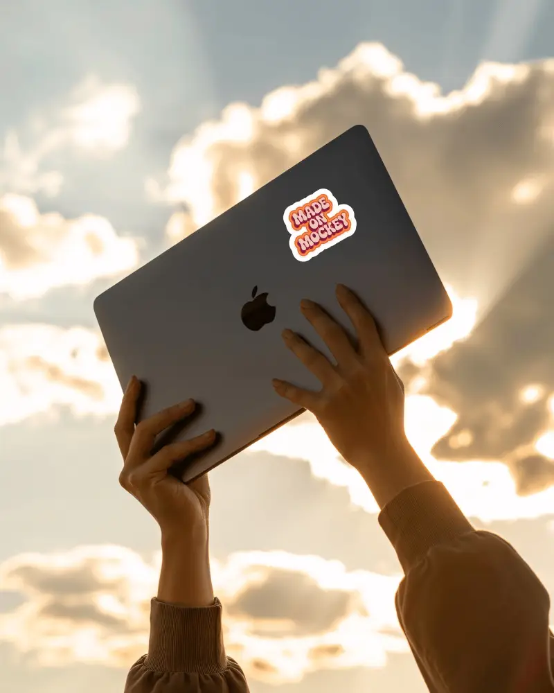 Sticker Mockups Laptop Held Up Against Sunlit Sky With Clouds And Inspirational Outdoor Lighting