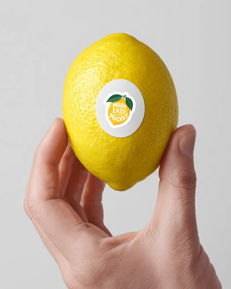 Lemon Sticker Mockup Round Label On Fresh Citrus Held By Hand Clean White Background