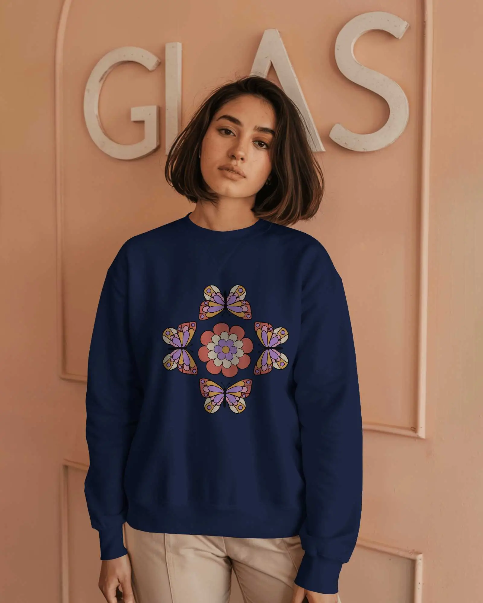 Indoor Sweatshirt Mockup Female Model In Light Grey Crewneck Against Peach Wall With Glass Sign Soft And Modern Aesthetic