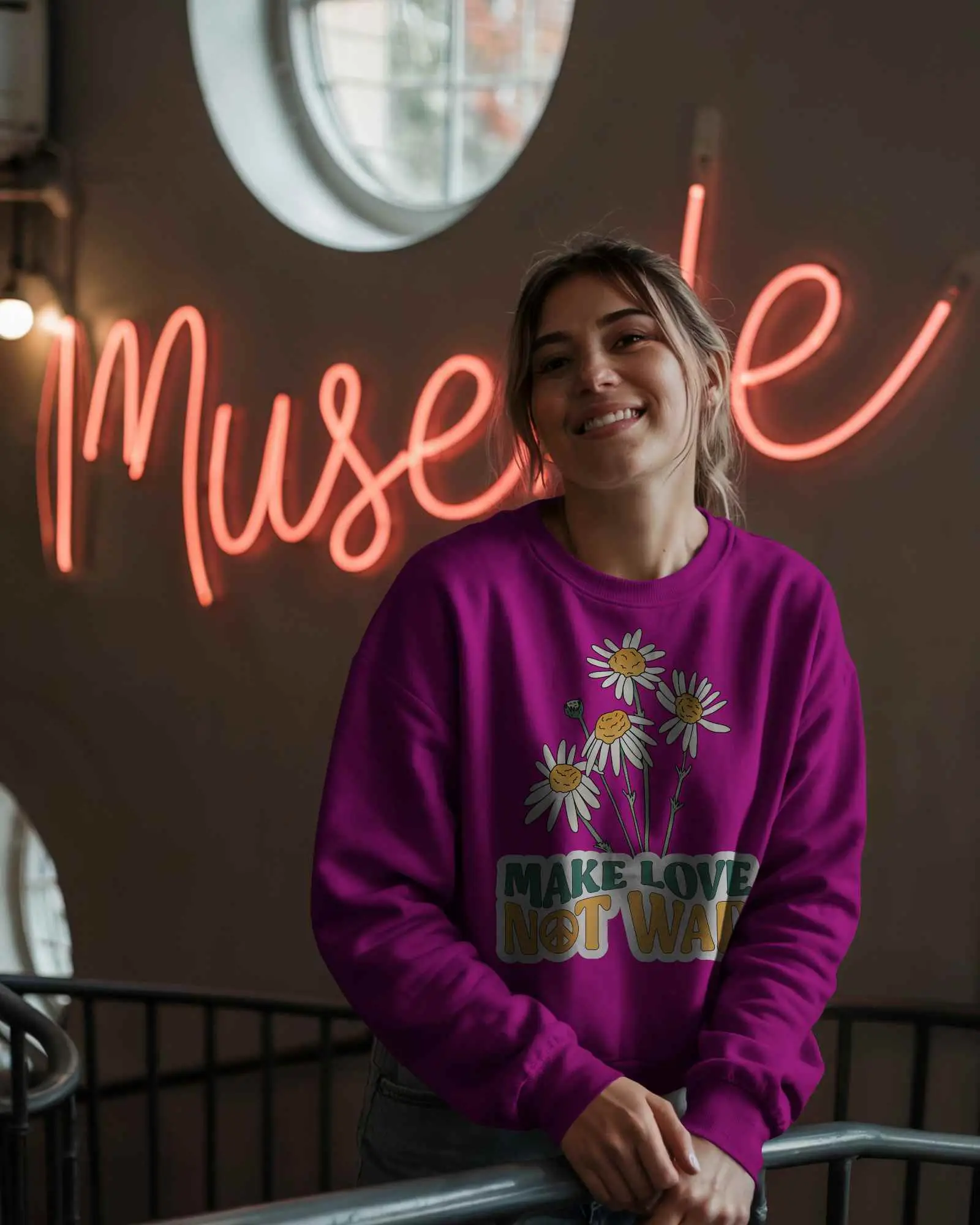 Neon Lit Indoor Sweatshirt Mockup Female Model Smiling Wearing Grey Crewneck By Railings Modern Artsy Vibe With Muse Sign