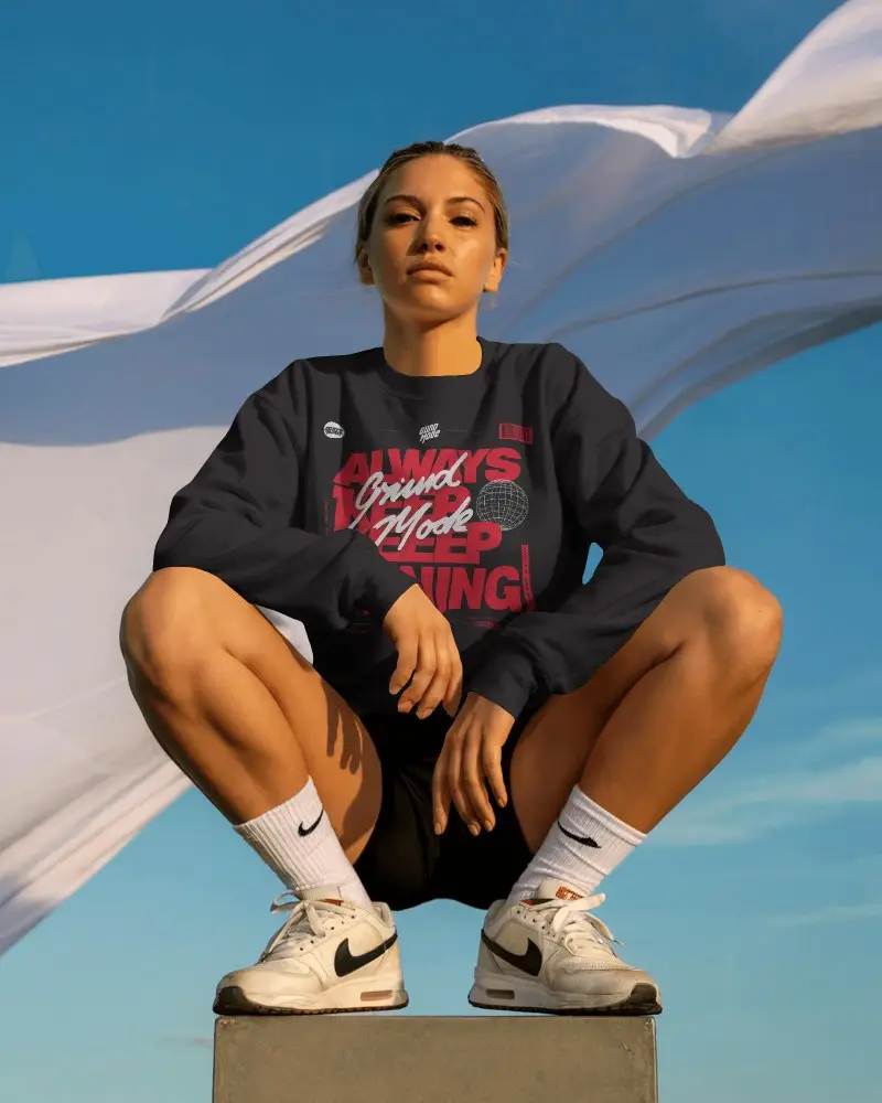 Outdoor Sweatshirt Mockup Female Model Squatting On Pedestal Blue Sky Background