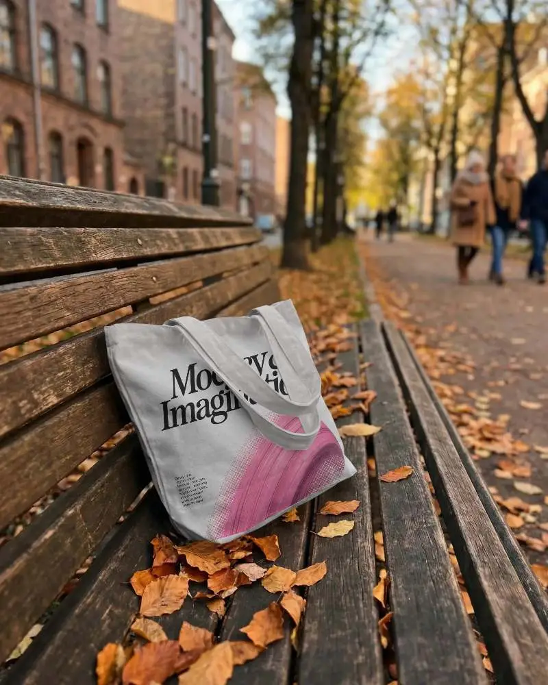 Reusable Cotton Tote Bag Mockup With Long Handles Placed On Vintage Bench In Fall Scene