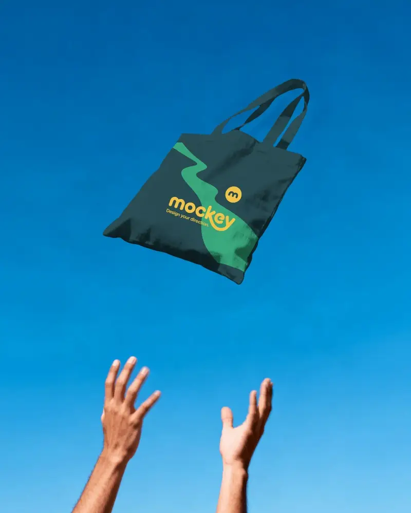 Floating Tote Bag Mockup Mid Air Catch Scene With Hands Reaching Up And Clear Blue Sky