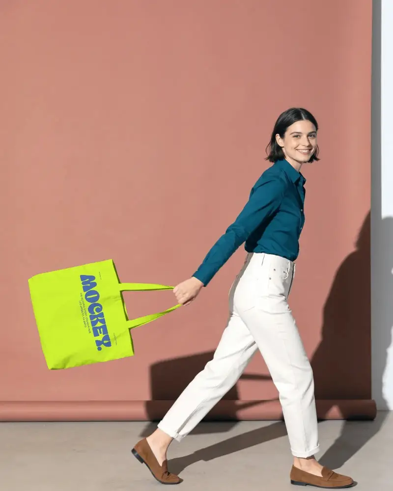 Walking Model Showcasing Plain Tote Bag Mockup For Eco Friendly Shopping Bag Designs
