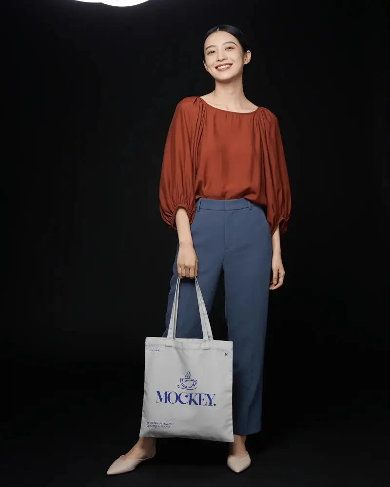 Stylish Casual Tote Bag Mockup With Female Model Standing Against Dark Background