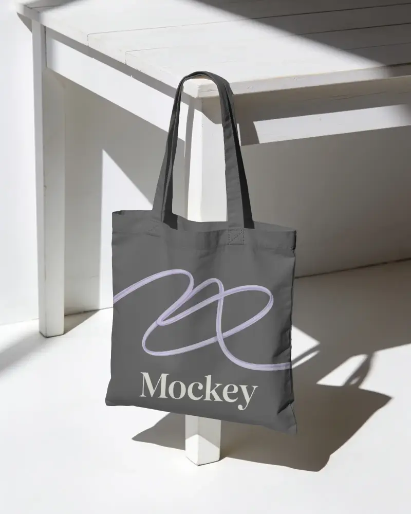 Eco Friendly Reusable Tote Bag Mockup Hanging From Table Edge For Daily Grocery Shopping