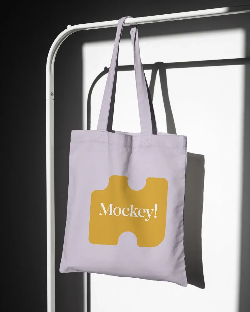 Minimalist Cotton Tote Bag Mockup Hanging On White Stand For Custom Design Showcase