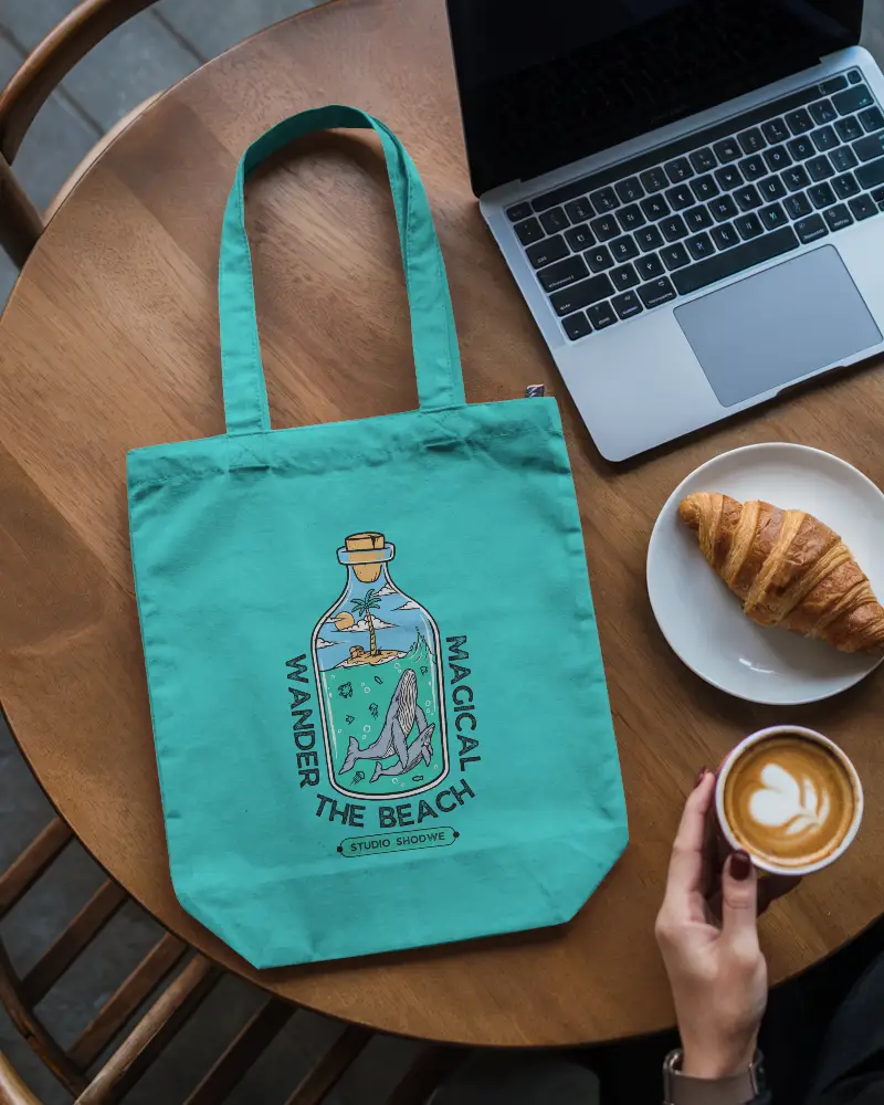 Cafe Scene Tote Bag Mockup On Wooden Table With Laptop Croissant And Latte In Modern Coffee Shop 0293